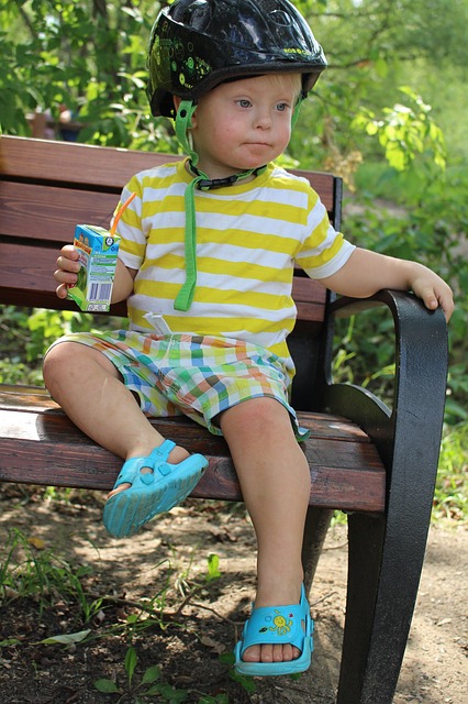 Boy with Down Syndrome sitting on a bench.