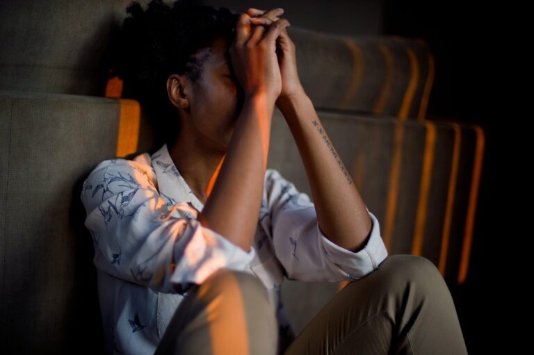 a person sitting with their head in their hands looking stressed
