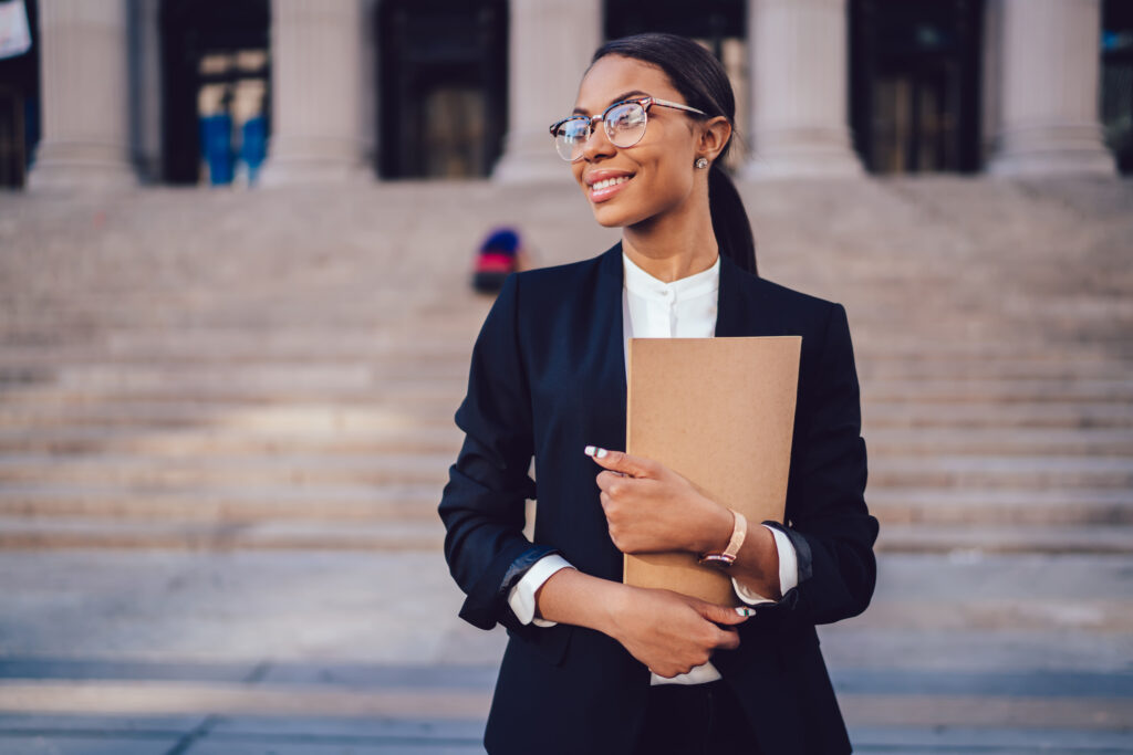 A woman stands outside a court building wearing an elegant dark blue suit